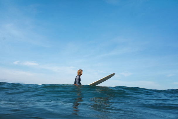 Surf In Ocean. Surfer On Surfboard Swimming In Sea. Surfing As Active Lifestyle. Blue Water And Beautiful Sky On Background. - Foto, afbeelding