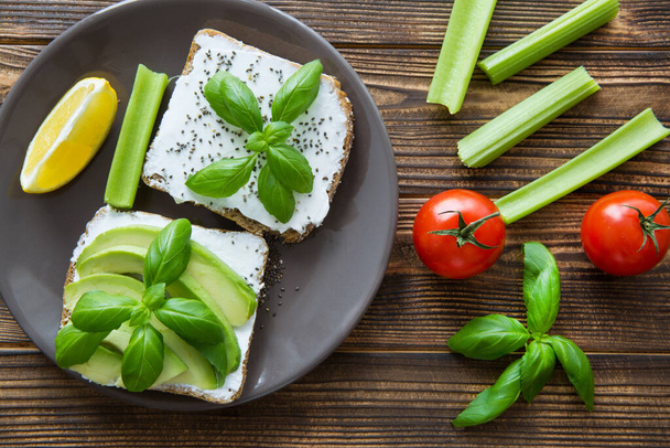 Tasty avocado sandwiches with cherry tomatoes with fresh basil leaves on brown rustic table  - Foto, Imagem