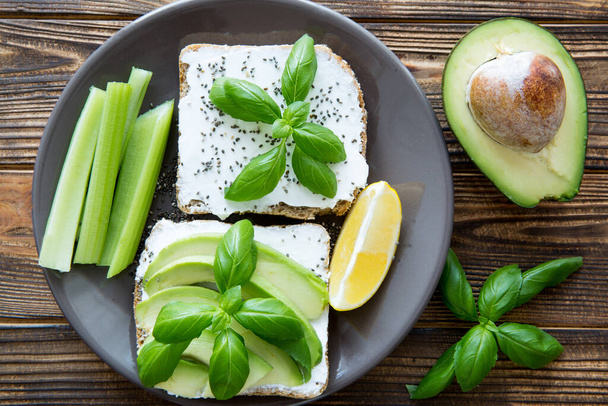 A plate of healthy snack. Avocado sandwiches with celery sticks, goat cheese, quinoa and a slice of lemon. Top view.  - Foto, Imagem