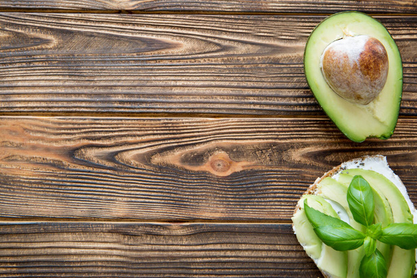Avocado sandwich with cream goat cheese on brown wooden table. Top view. Free space for text, copy space.  - Photo, image