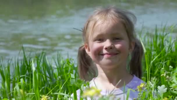 Retrato de una niña sonriente en la hierba - Imágenes, Vídeo
