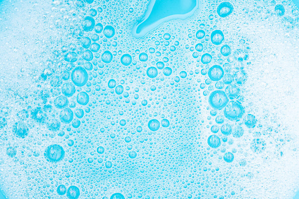Su yüzeyinde köpüklü beyaz köpük, sabun ve mavi banyoyla yıkama tozu, soyut şeffaf arka plan kabarcığı. - Fotoğraf, Görsel