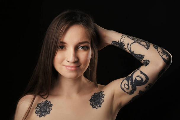 Young woman with tattoo on dark background - 写真・画像
