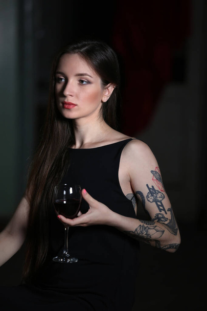 Mujer joven con copa de vino tinto en la habitación
 - Foto, Imagen