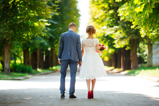Bride and groom on their wedding day, walking outdoors in nature. - 写真・画像