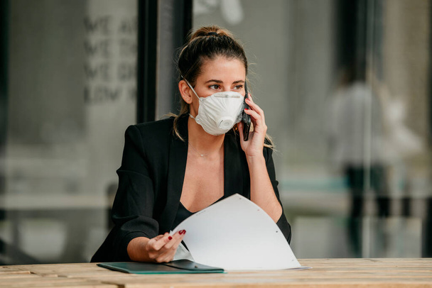 junge Geschäftsfrau telefoniert mit medizinischer Maske - Foto, Bild