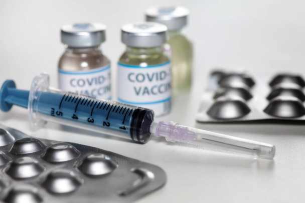 Injection syringe with vaccine bottles and medicine in selective focus for treatment of COVID-19 patients - 写真・画像