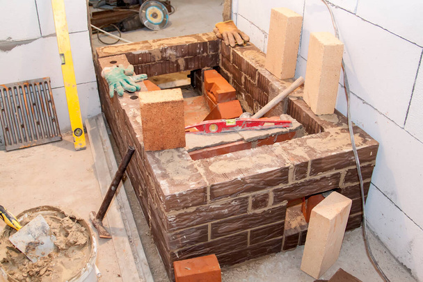 Poêle de sauna qui est construit à partir de matériaux résistant au feu dans l'intérieur non développé disposé de blocs de mousse dans la maison de campagne en construction - Photo, image