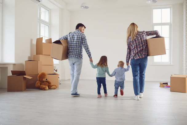 Happy family with children moving with boxes in a new apartment house. - Foto, afbeelding