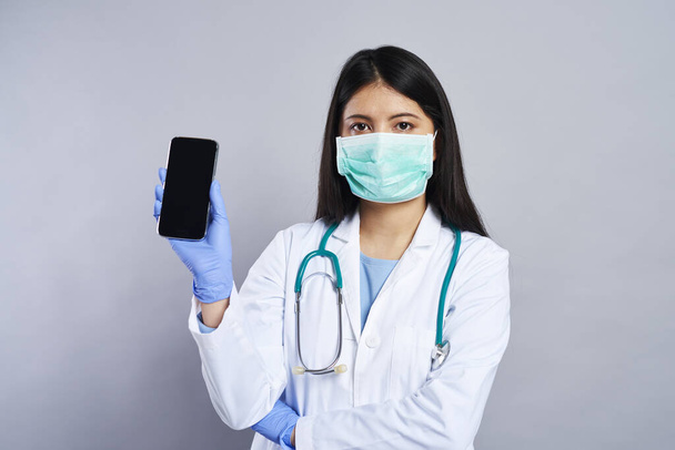 Ázsiai orvos kezében egy mobiltelefon - Fotó, kép