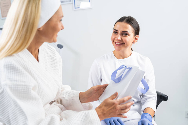 Cheerful beautician smiling at her pleased patient - Foto, imagen