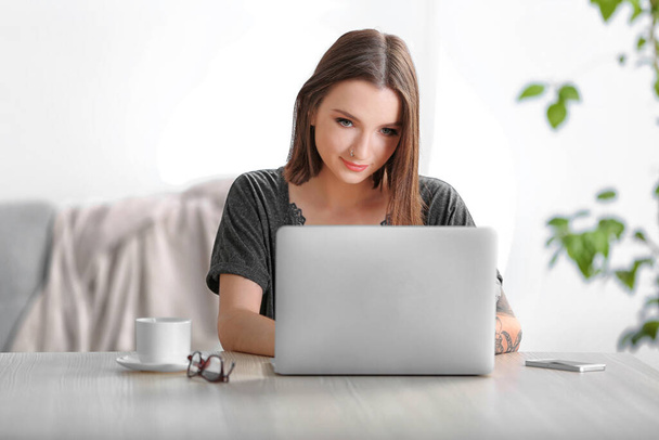 Femme assise à la table et travaillant avec un ordinateur portable
 - Photo, image