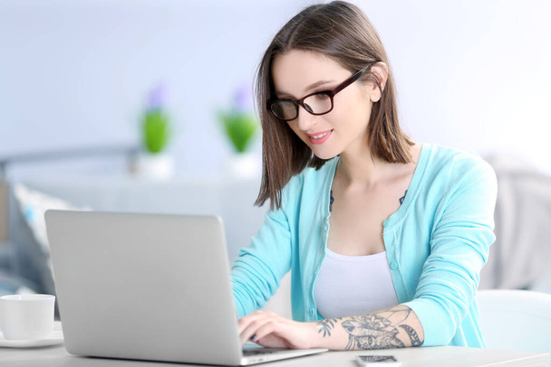 Жінка сидить за столом і працює з ноутбуком
 - Фото, зображення