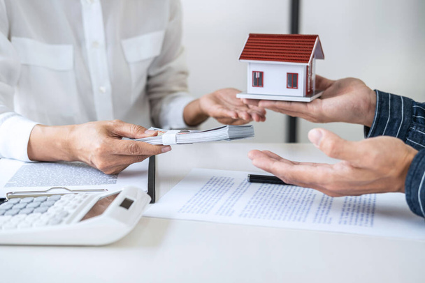 Agent brokerski ds. nieruchomości konsultuje się z klientem przy podejmowaniu decyzji o podpisaniu formularza ubezpieczenia i wysyłaniu modelu domu do klienta po zatwierdzeniu, oferty kredytu hipotecznego modelu domowego i ubezpieczenia domu. - Zdjęcie, obraz
