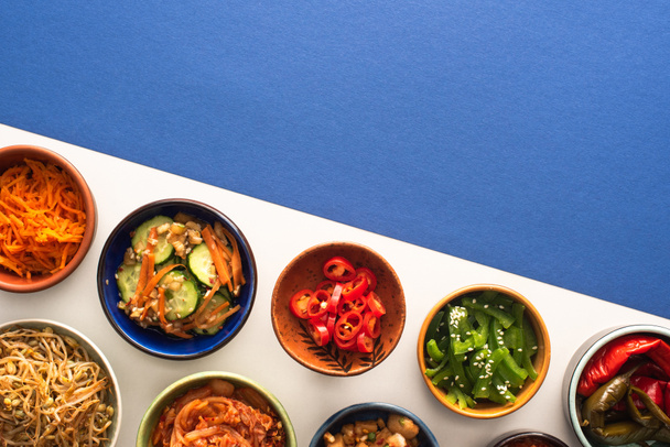 top view of bowls with korean traditional side dishes on blue and white  - Photo, Image