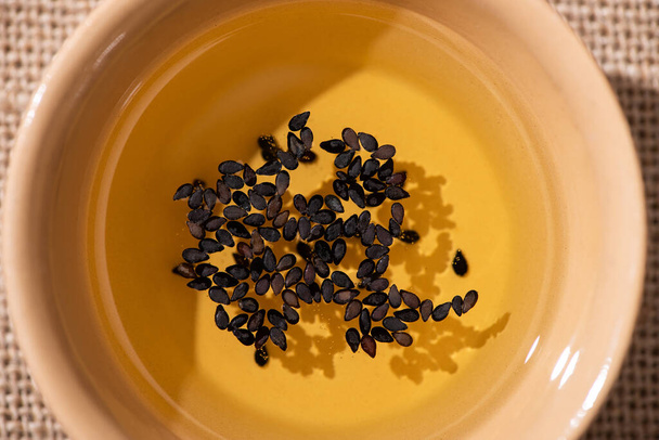 vista superior del aceite con sésamo negro en tazón
  - Foto, Imagen