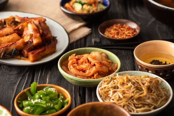 foco selectivo de kimchi picante cerca de topokki y guarniciones coreanas
  - Foto, Imagen