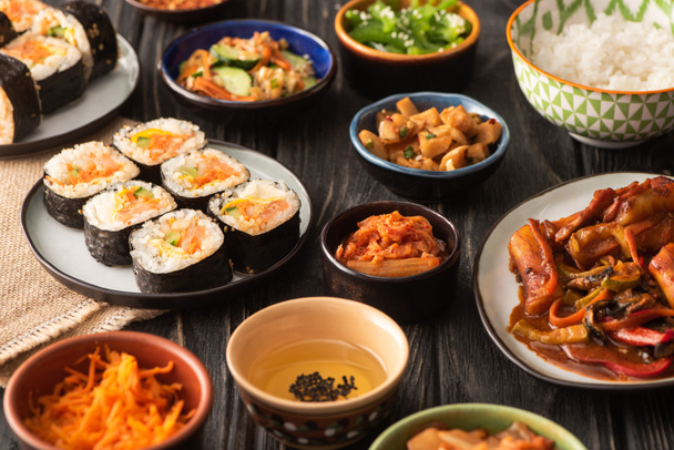 messa a fuoco selettiva di gimbap tradizionale e kimchi vicino gustosi piatti coreani sulla superficie di legno
  - Foto, immagini