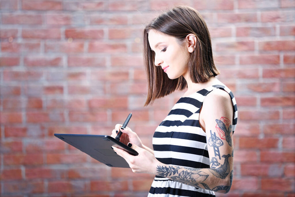Woman with tablet on brick wall background - Photo, Image