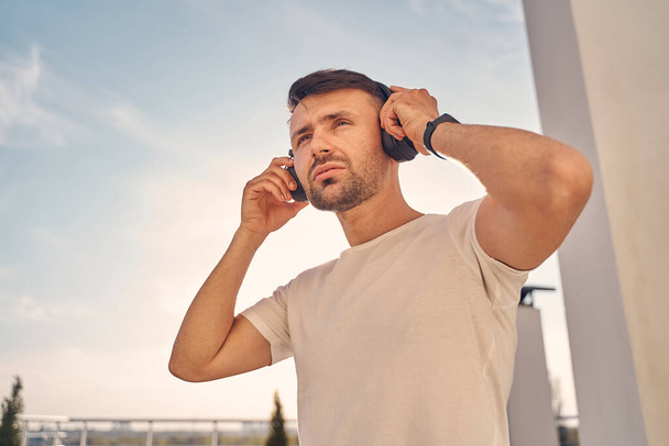 Handsome brunette man listening to music outside - Foto, Bild
