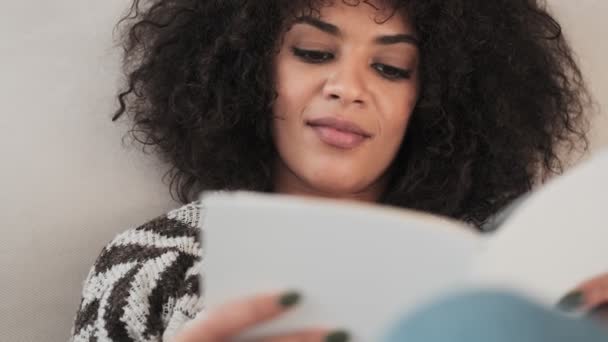 Amazing pretty african curly woman indoors at home reading book - Filmati, video