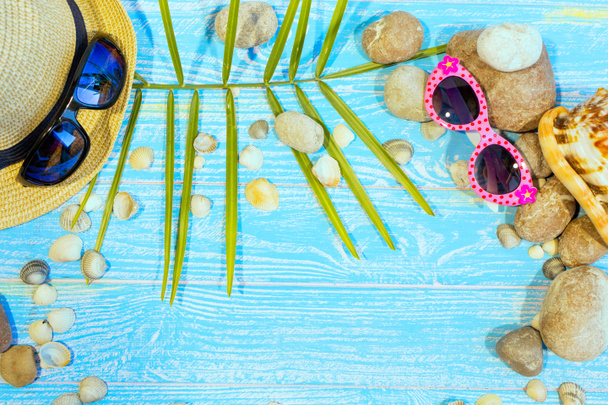 青いボードのアクアマリン色の背景にビーチアクセサリーのバナー。帽子、サングラス、貝殻、海の石。旅行や観光。夏休みのコンセプト. - 写真・画像