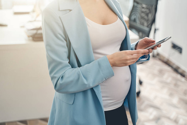 Young pregnant woman using cellphone at work - Φωτογραφία, εικόνα