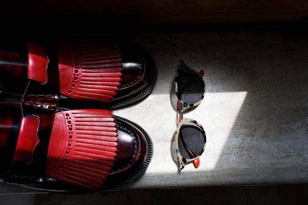 Pánské černé kožené boty. Červené kožené vložky. Vedle těch brýlí. Světlo a stín. - Fotografie, Obrázek
