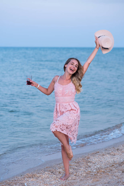 girl with a ball on the beach. young woman in hat on the beach. young woman in pink dress on the beach. Holidays at sea. - Foto, Bild
