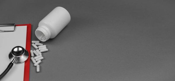 Таблетки та стетоскоп на сірому фоні, простір для копіювання
 - Фото, зображення