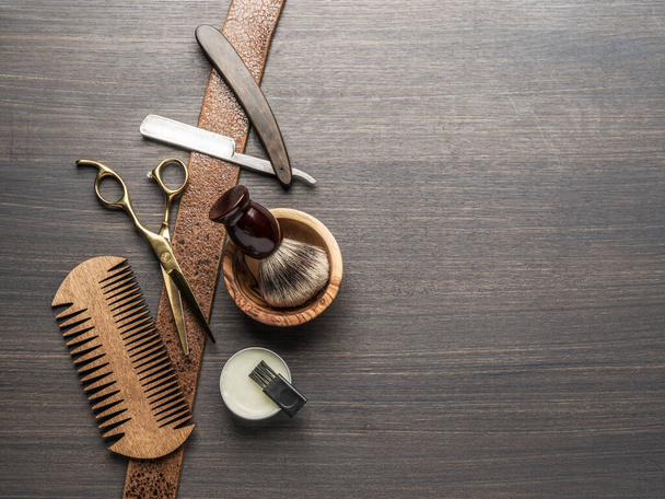 Classic grooming and hairdressing tools on wooden background. Top view on barbershop instruments  laying on dark wooden table. - 写真・画像