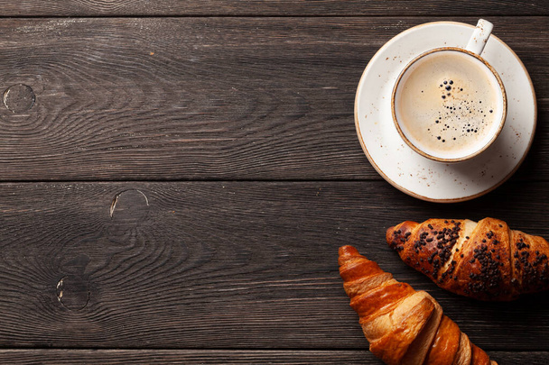 Káva a croissanty na dřevěném stole. Horní pohled s mezerou pro kopírování - Fotografie, Obrázek