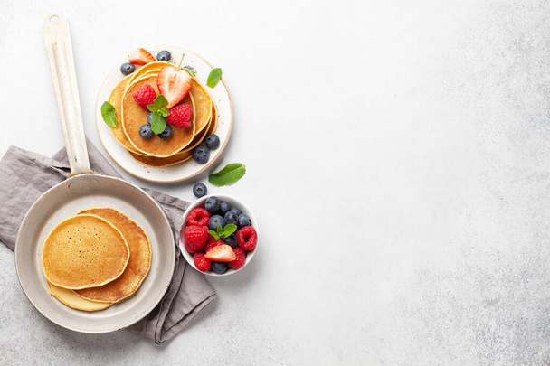 Heerlijke zelfgemaakte pannenkoeken met zomerbessen als ontbijt. Morgenmaaltijd. Bovenaanzicht met kopieerruimte - Foto, afbeelding