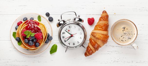 Leckere hausgemachte Pfannkuchen mit Sommerbeeren und Marmelade, Croissants und Kaffee zum Frühstück. Ansicht von oben. Frühstückskonzept - Foto, Bild