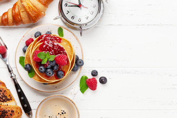 Leckere hausgemachte Pfannkuchen mit Sommerbeeren und Kaffee zum Frühstück. Draufsicht mit Kopierraum - Foto, Bild