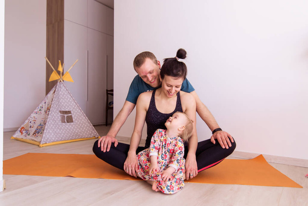 Full young family goes sports at home togetherness. Mom dad baby kid doing yoga exercises. Love harmony idyll. Leisure healthy lifestyle. Activity morning. mental health resilience contented emotion - Fotoğraf, Görsel