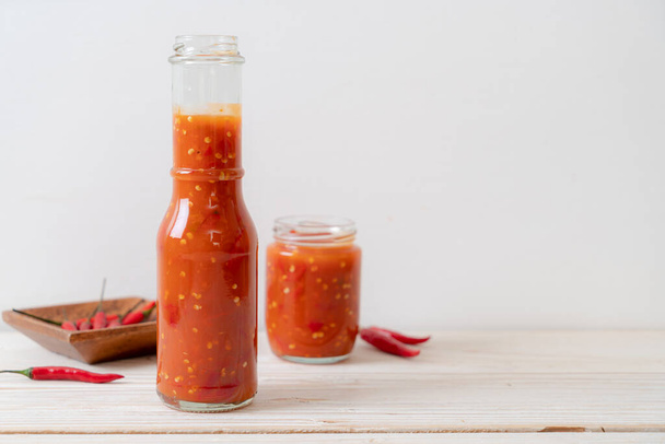 chilli or chilli sauce in bottle and jar on wwod background - Фото, изображение