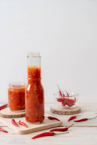 chilli or chilli sauce in bottle and jar on wwod background - Foto, imagen
