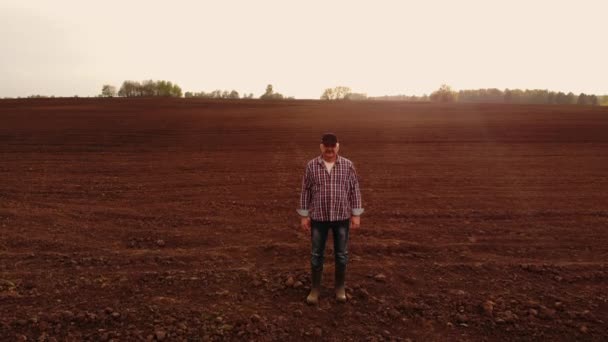 fotografia aerea il drone segue un contadino che cammina attraverso un campo arato con terra. Volare intorno e seguire gli agricoltori vista dall'alto
 - Filmati, video