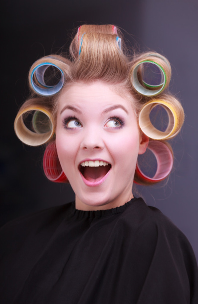 Funny cheerful blond girl hair curlers rollers by hairdresser in salon - Фото, зображення