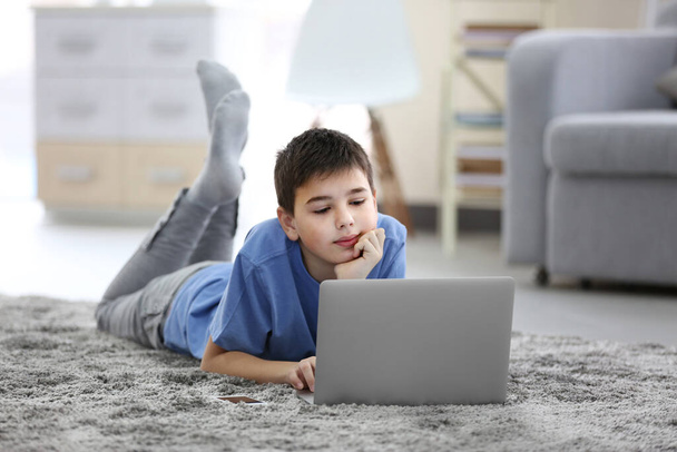 Little boy using laptop on a floor at home - Foto, afbeelding