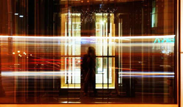 lange belichtingstijd weerspiegeld in het glas in de stad auto 's bewegen snel kleurrijke lichten - Foto, afbeelding