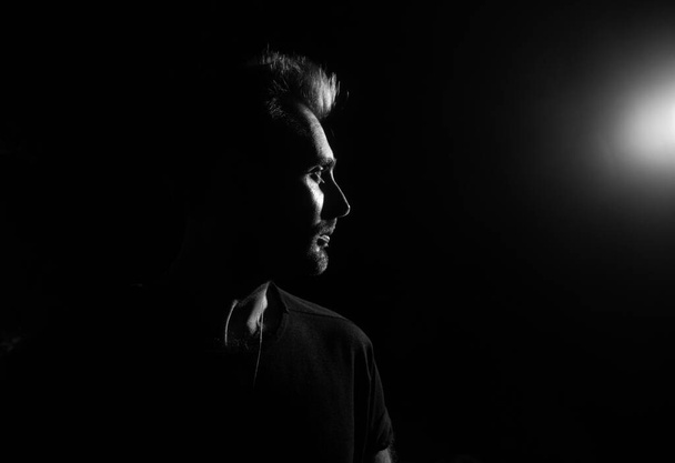 Dramatic profile portrait of male person on dark background - Photo, Image