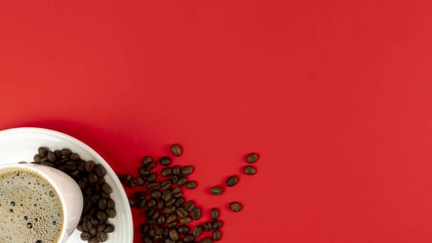 Ένα φλιτζάνι φρέσκο καφέ και κόκκους καφέ σε κόκκινο φόντο. ελεύθερος χώρος για κείμενο - Φωτογραφία, εικόνα