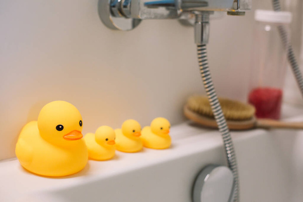 Accessoires de bain et quatre canard jaune caoutchouc sont debout sur la salle de bain blanche
 - Photo, image