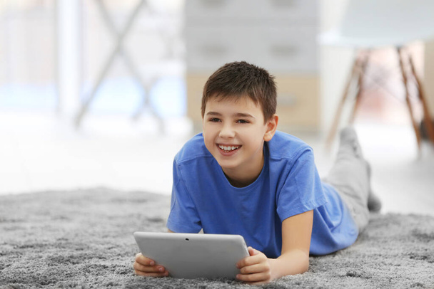 Niño pequeño usando la tableta en un piso en casa
 - Foto, Imagen