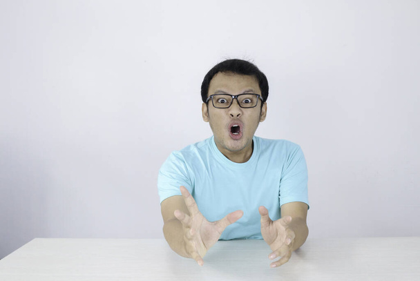 Wow and shocked face of Young Asian man with open hand gesture. Advertising model concept with blue shirt. - Zdjęcie, obraz