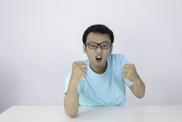 Angry and hate face of Young Asian man in blue shirt with angry hand gesture. - Фото, изображение