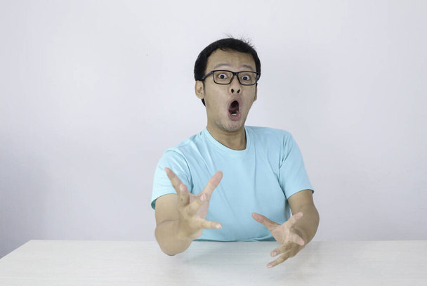 Wow and shocked face of Young Asian man with open hand gesture. Advertising model concept with blue shirt. - Фото, изображение