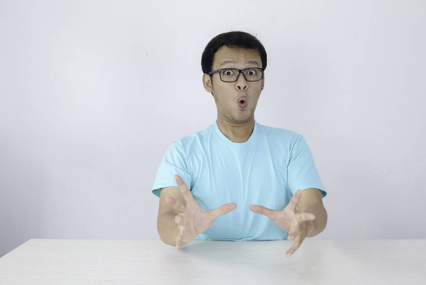 Wow and shocked face of Young Asian man with open hand gesture. Advertising model concept with blue shirt. - Фото, зображення